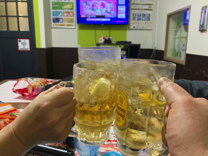 大きなジョッキのハイボールで乾杯する手元とカラオケルームの様子
