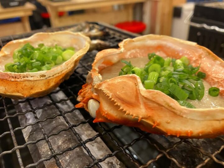 カニ味噌とネギが入った甲羅を網焼きしている様子