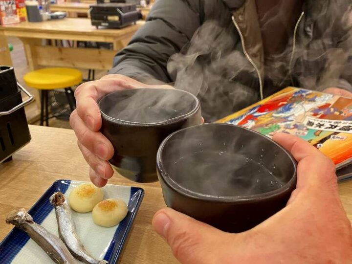 磯丸水産で湯気の立つ芋焼酎のお湯割りで乾杯
