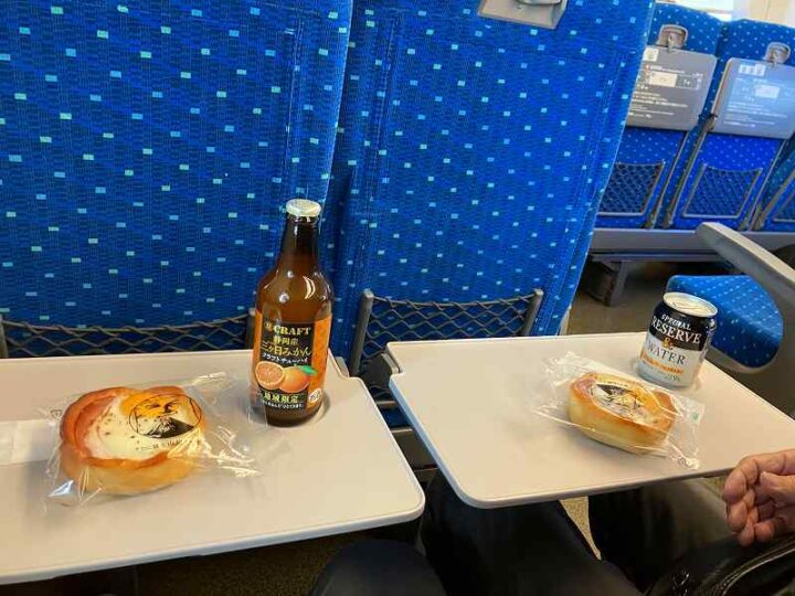 新幹線車内テーブルに並ぶパンとクラフトチューハイ
