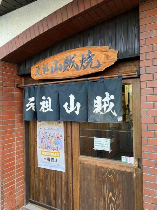 元祖山賊村井店の入口暖簾と看板