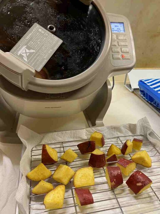 揚げたさつまいもを網で油切りしている様子