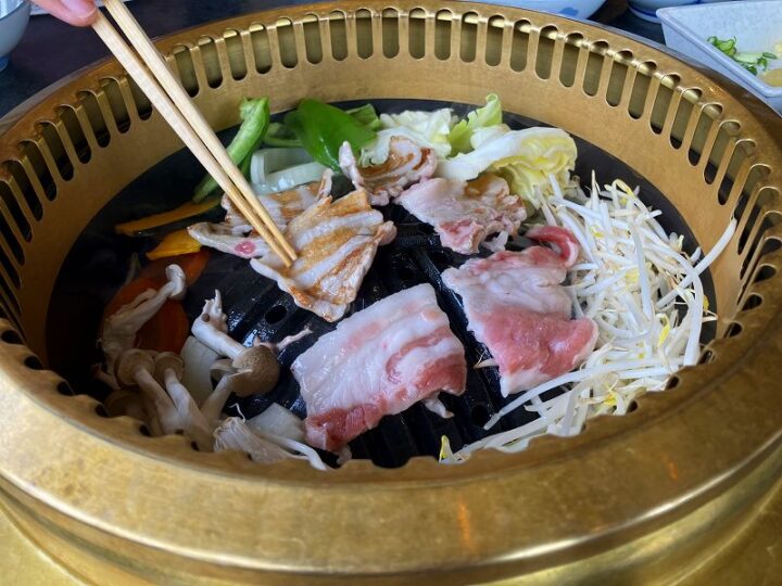 奥山きじ亭のジンギスカン鉄板で豚肉を焼く様子