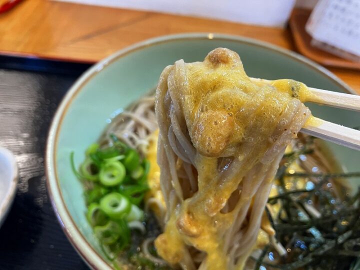 箸で持ち上げた納豆そば 納豆と玉子がそばにからむ様子