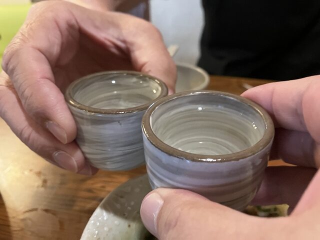 紀土純米吟醸と雨後の月辛口純米酒をおちょこで乾杯する様子