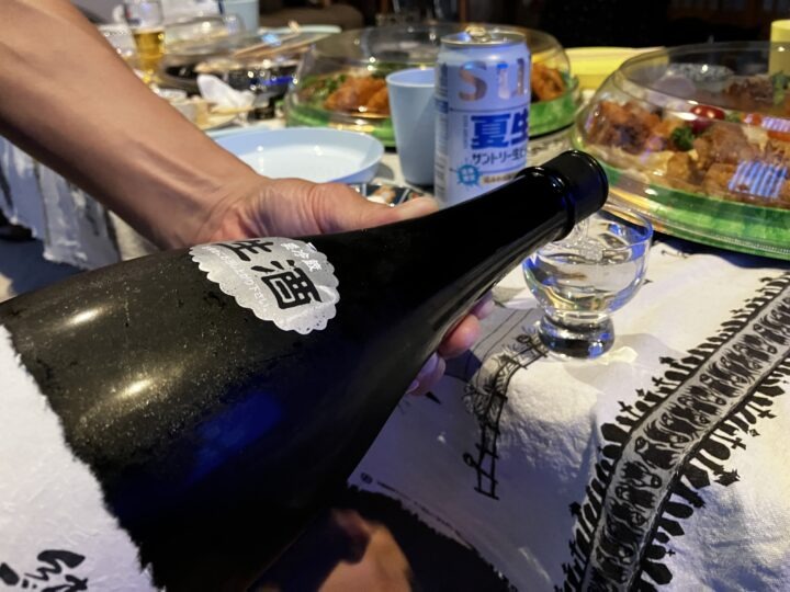 手元の冷酒グラスへ注がれる透き通った鳳凰美田の純米大吟醸生酒