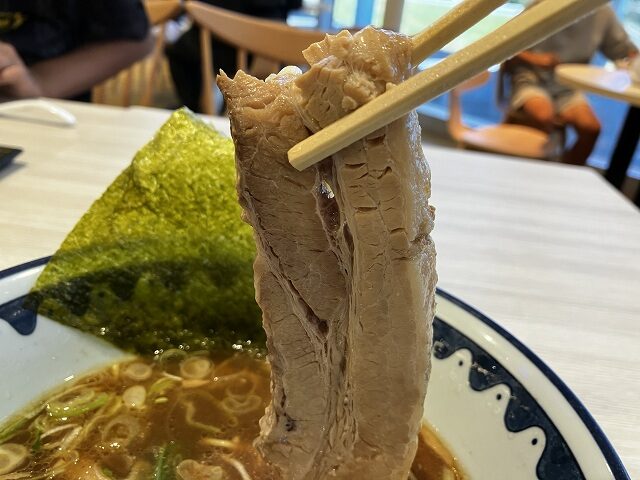 箸で持ち上げた麺屋道神の厚切りチャーシュー