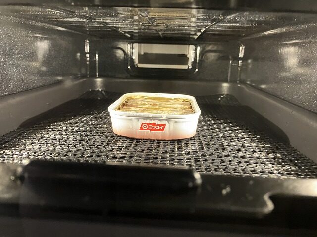 魚焼きグリルの中で缶ごと温めているオイル・サーディン