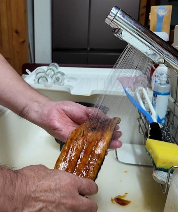 購入したうなぎの蒲焼きを流水で洗う様子