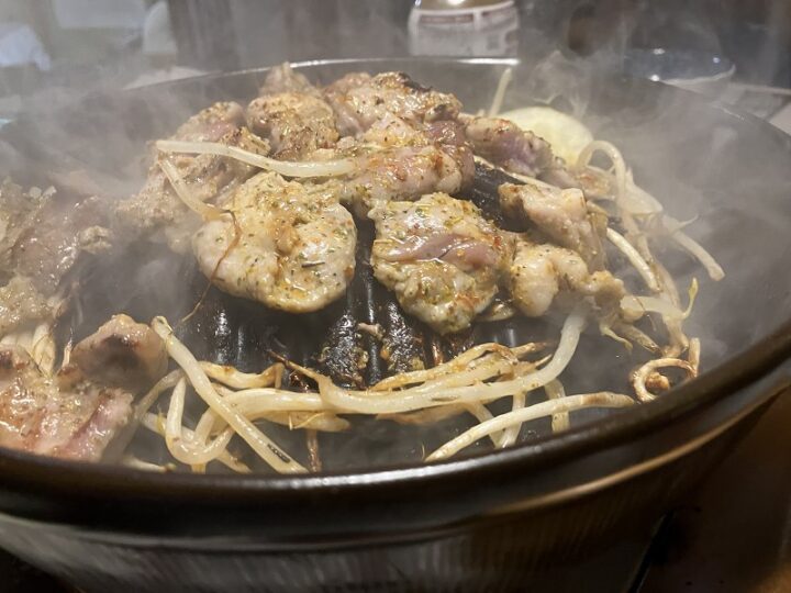 ジンギスカン鍋の中央で豪快に焼かれる豚肉と周囲で旨みを吸うもやし
