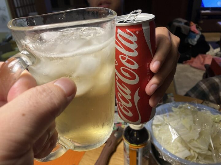 ハイボールジョッキと真っ赤なコカ・コーラの缶で乾杯する手元
