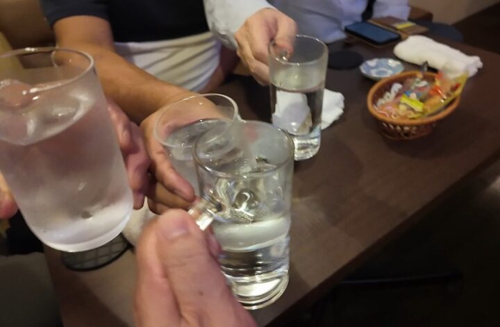 グラスを寄せて乾杯する手元とテーブルに置かれた駄菓子のカゴ