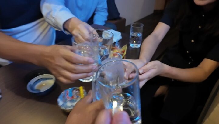 赤坂たけ田の店内で仲間やママさんとグラスを合わせて賑やかに乾杯するシーン