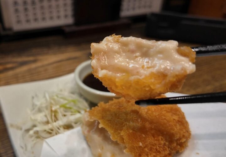 お箸で持ち上げたカニクリームコロッケの断面からとろりと溢れ出る濃厚なクリーム