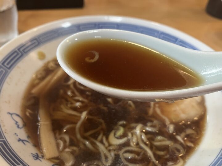 レンゲですくい上げた透き通るような濃口醤油ベースのスープ