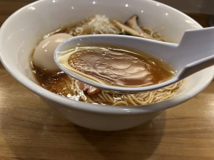 レンゲですくった表面にきらめく香味油が美しい醤油スープ